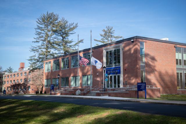 Exterior of Parenzo Hall with two flags flying in front and blue skies in the background.