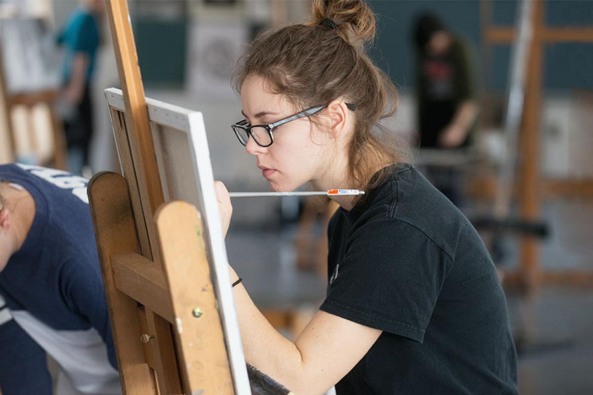 A student works on their painting while in class.
