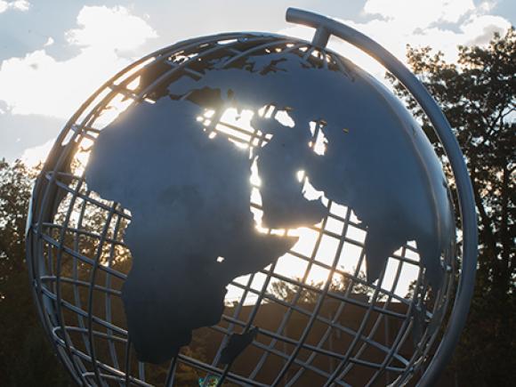 Sunlight shines through the globe sculpture on the campus green