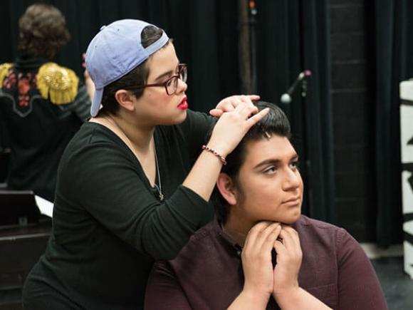 Two students preparing hair and makeup before a theatre production.