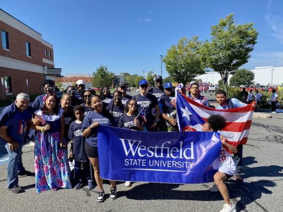 Representatives of Wesfield State wearing navy blue t-shirts and holding Westfield State University banners, as well as the Puerto Rican flag.