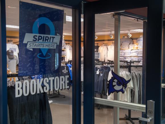 Campus bookstore exterior featuring glass windows with word "Bookstore" and "Spirit Starts Here" with owl spirit mark.
