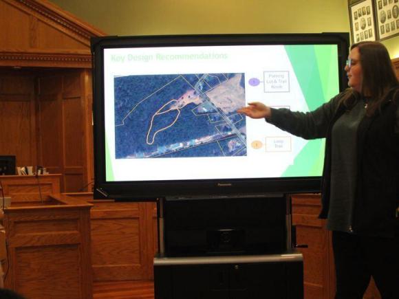 Danielle Ansel, a GPS major, presents at the Westfield Conservation Commission's meeting earlier this month about the proposed Pitoniak trails. She stands in front of a large screen gesturing at the paths suggested by her class.