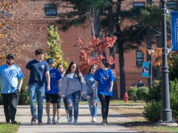 A group of seven students walk across the Westfield State University campus.