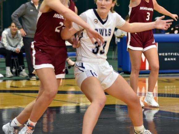 Jordan Grant, a senior at Westfield State. She is a basketball player and is competing against another university. She's wearing a white Owls uniform and guards against a competitor in a maroon uniform.