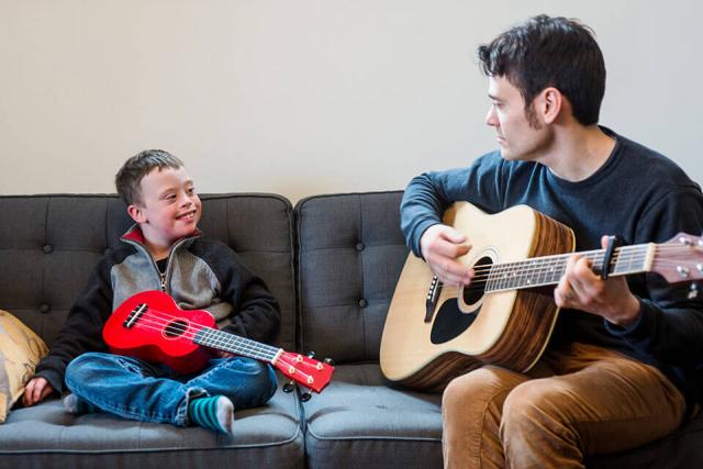 Music teacher giving a small child guitar lessons.