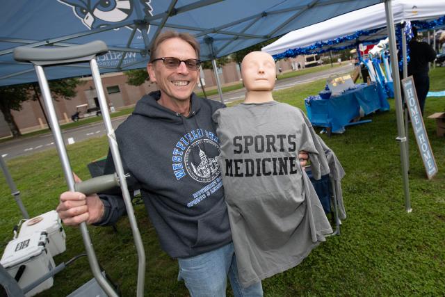 Movement Science faculty member wearing sunglass holding a sweatshirt that says Sports Medicine.