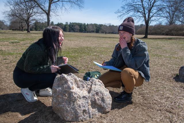 Two Earth System Science students looking at a rock laughing.