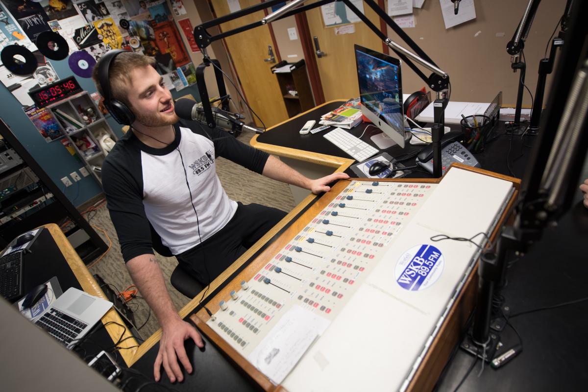 student using soundboard in the campus radio station WSKB