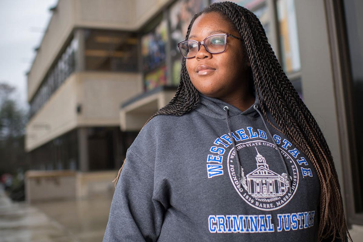 A student poses for a photo while wearing a sweatshirt that says “Westfield State Criminal Justice.”