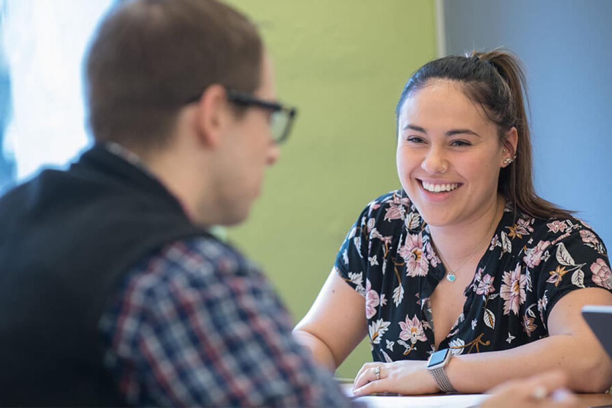 A student smiling across the table at someone.