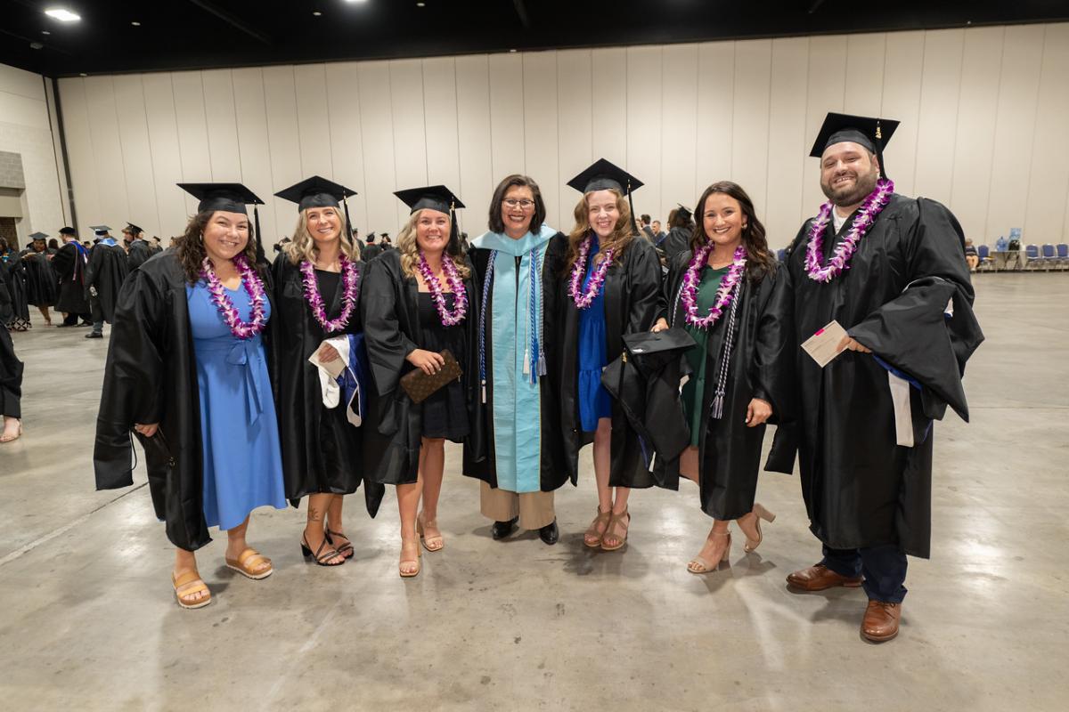 School counseling graduate students in caps and gowns at commencement ceremony.