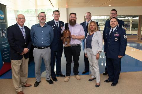 Dr. Jesse Johnson holds a Spartan trophy and poses with President Thompson, Justin Marques, and fellow veterans of the Air Force in uniform.