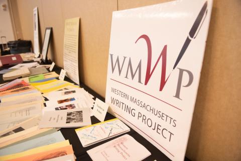A table covered with various papers, newspaper clippings, and a large WMWP poster on it.