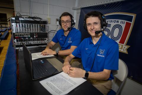 Brayden Cutler and Zachary Bianco broadcasting intramural events on campus. They wear blue polos and black headsets, which they use to do play-by-play commentary for sports games at the University.
