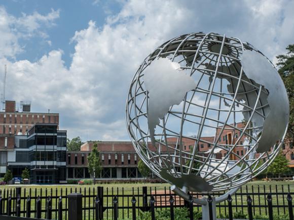 The globe sculpture on the campus green with the Ely Campus Center in the background