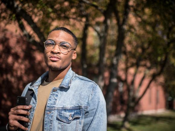 Student looking at the camera on the campus green in front of Courtney Hall