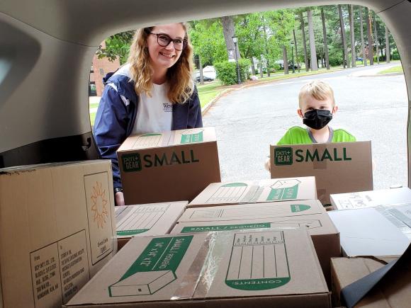 Photo of volunteers taking boxes of donations out of a car