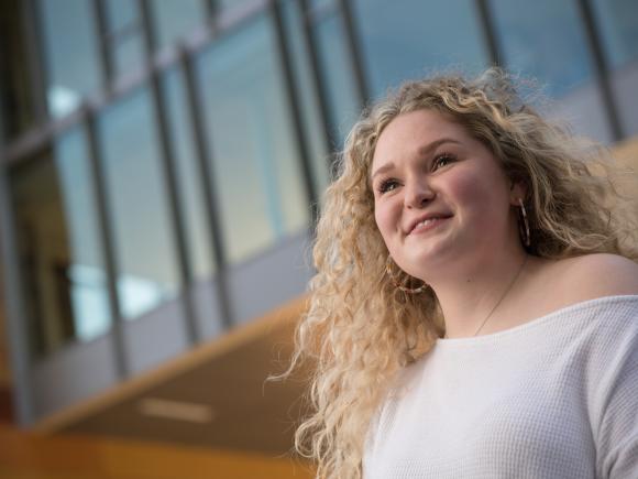 Female student with blonde, curly hair, outside of University Hall