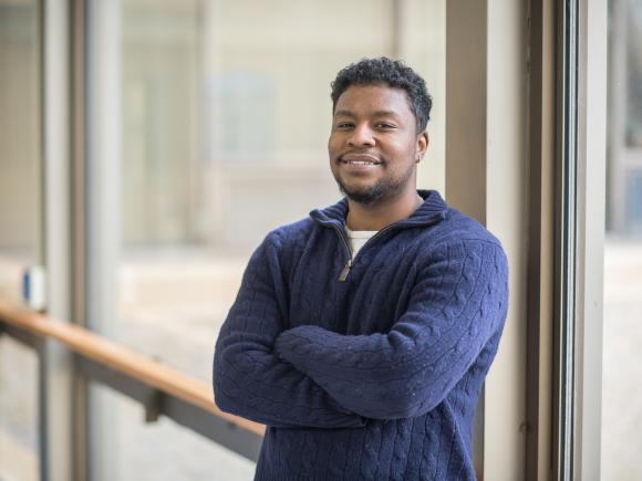 Male student in blue sweatshirt smiling at camera