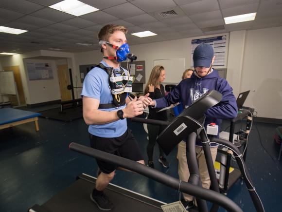 Male connected to monitoring equipment running on a treadmill in the Woodward Center