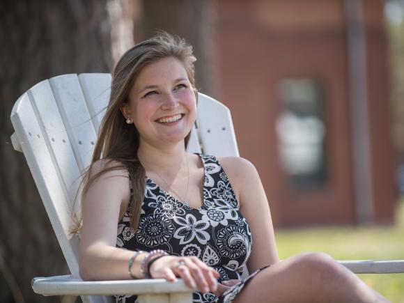 WSU student Rebecca Rokne smiles as she sits in an Adirondack chair on the campus green