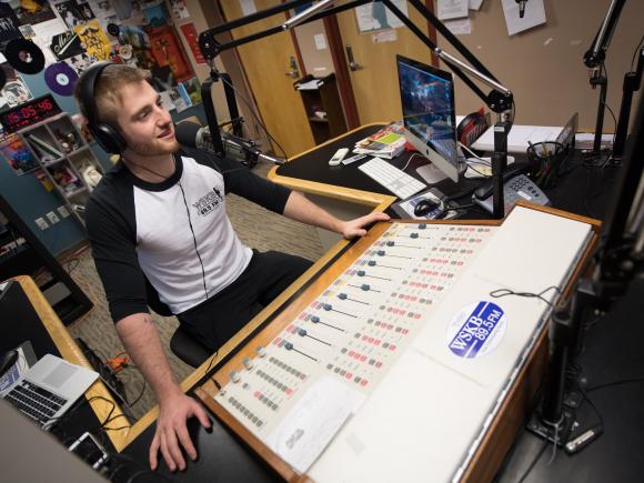 student using soundboard in the campus radio station WSKB