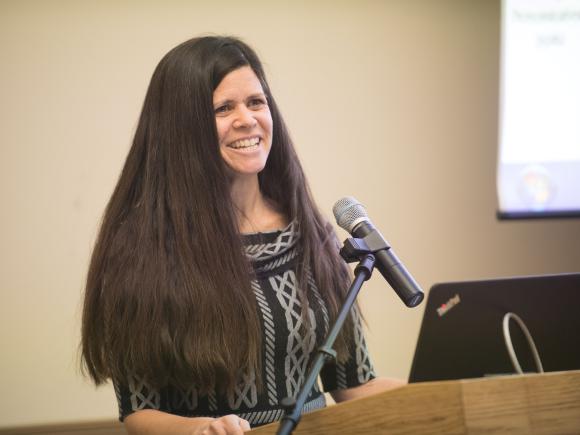 Dr. Catherine Savini stands at a podium and speaks into a microphone