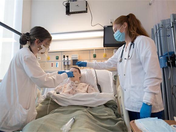 Two nursing students learn in a simulation learning lab.