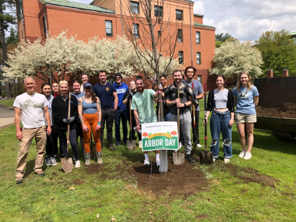 A group of students and faculty surround a tree planting.