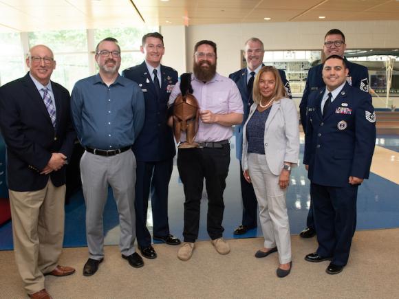 Dr. Jesse Johnson holds a Spartan trophy and poses with President Thompson, Justin Marques, and fellow veterans of the Air Force in uniform.