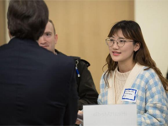 A student talks with two people from iHeartMedia, Inc.