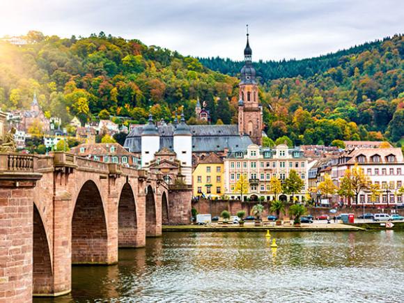Buildings line a picturesque waterway crossed by a bridge in Germany.
