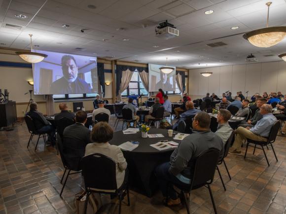 Attendees sit around tables as they listen to the speaker present on hate-crimes.