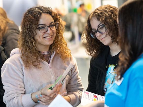 Multiple students smile while engaging in conversation.