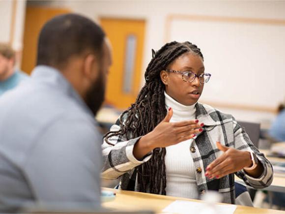 Two students engage in discussion in a classroom setting.