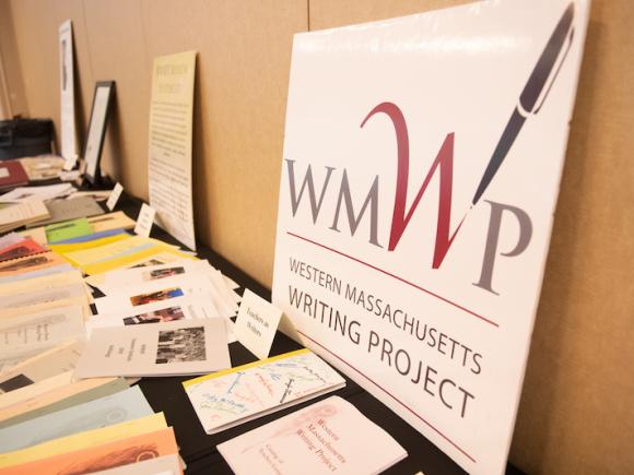 A table covered with various papers, newspaper clippings, and a large WMWP poster on it.