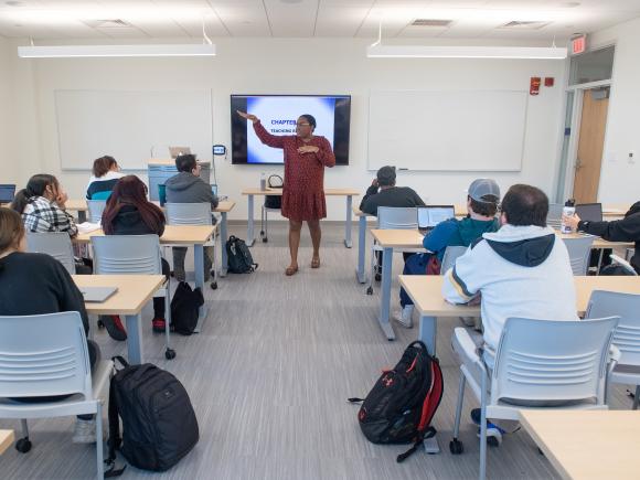 Teacher at the head of classroom in front of students