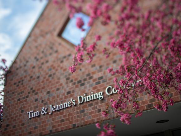 Exterior of Dining Commons featuring brick building with pink flowering trees.