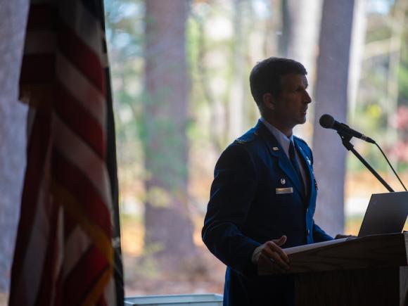 Colonel David Halasi-Kun stands next to an American flag while he addresses attendees for the 2023 Veteran's Day Ceremony.