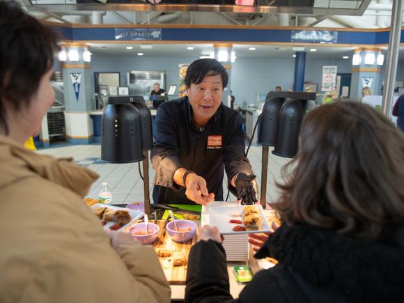 Chef Ming, from this fall's annual food snow. He's wearing a black shirt and extending his hand out to a customer who will be eating the homemade bings, Chinese streetfood crepes, he made.