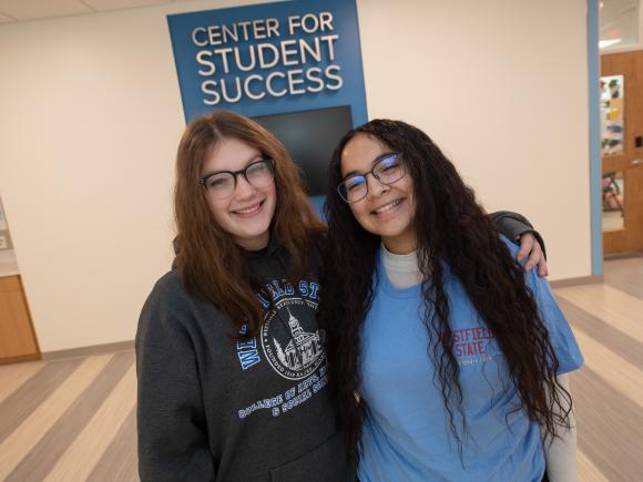 Two students wearing WSU sweatshirts smiling outside Center for Student Success.