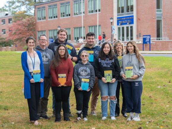 Historical Journal group photo featuring seven individuals comprising of faculty and students smiling holding the journal in front of Parenzo.