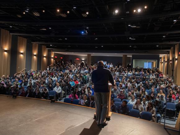 Accepted Student Day 2024. The photo shows Michael Mazeika, Director of Admission, speaking at a podium in the auditorium in Parenzo Hall. Hundreds of newly accepted students sit in the rows before him.