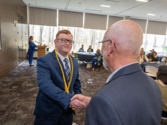 Student at Honors Symposium shaking hands with a faculty member.