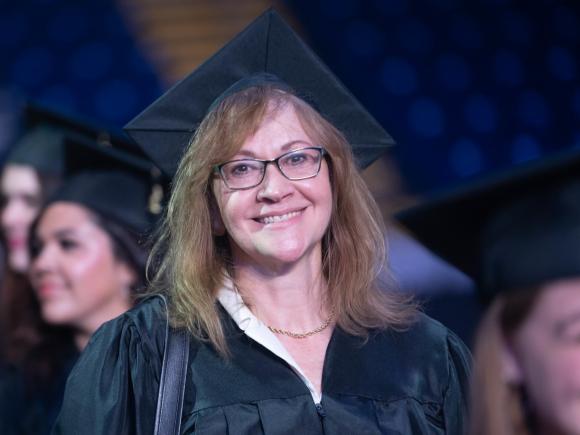 MPA student smiling at commencement wearing a cap and gown.