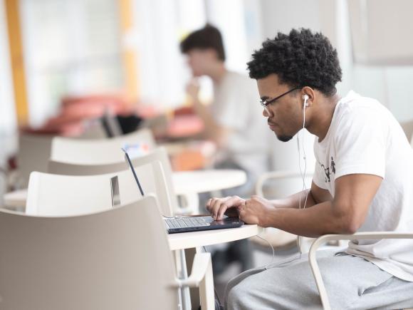 Student studying on campus while working on a laptop.