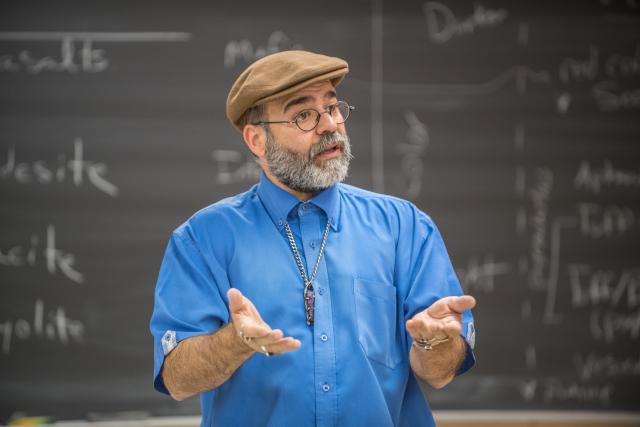 Image of professor Aaron Reyes lecturing in front of a chalkboard