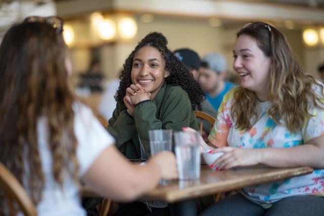 Smiling students seated in the dining commons 