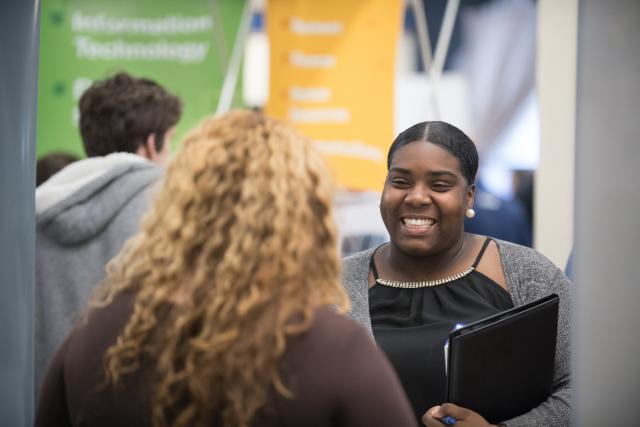 Smiling female talks with a prospective employer at the Career Fair